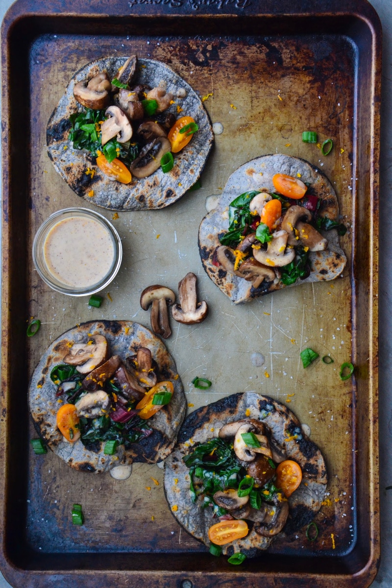 Veggie fajitas on a baking sheet with dairy-free sauce on the side.
