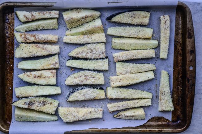 Coated fries with almond flour on a rimmed baking sheet.