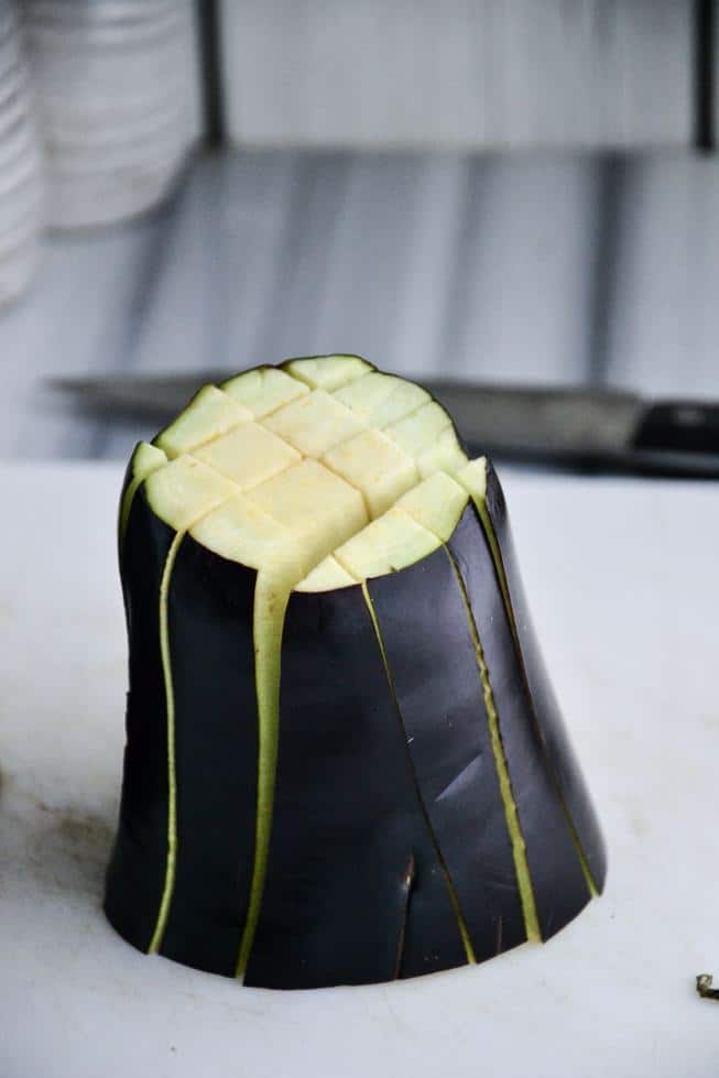 Eggplant being sliced for eggplant fries on a marble surface ready to go into the oven.