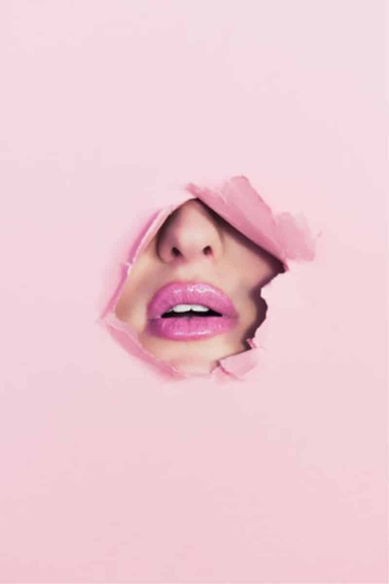 A face with pink lips coming through a pink background