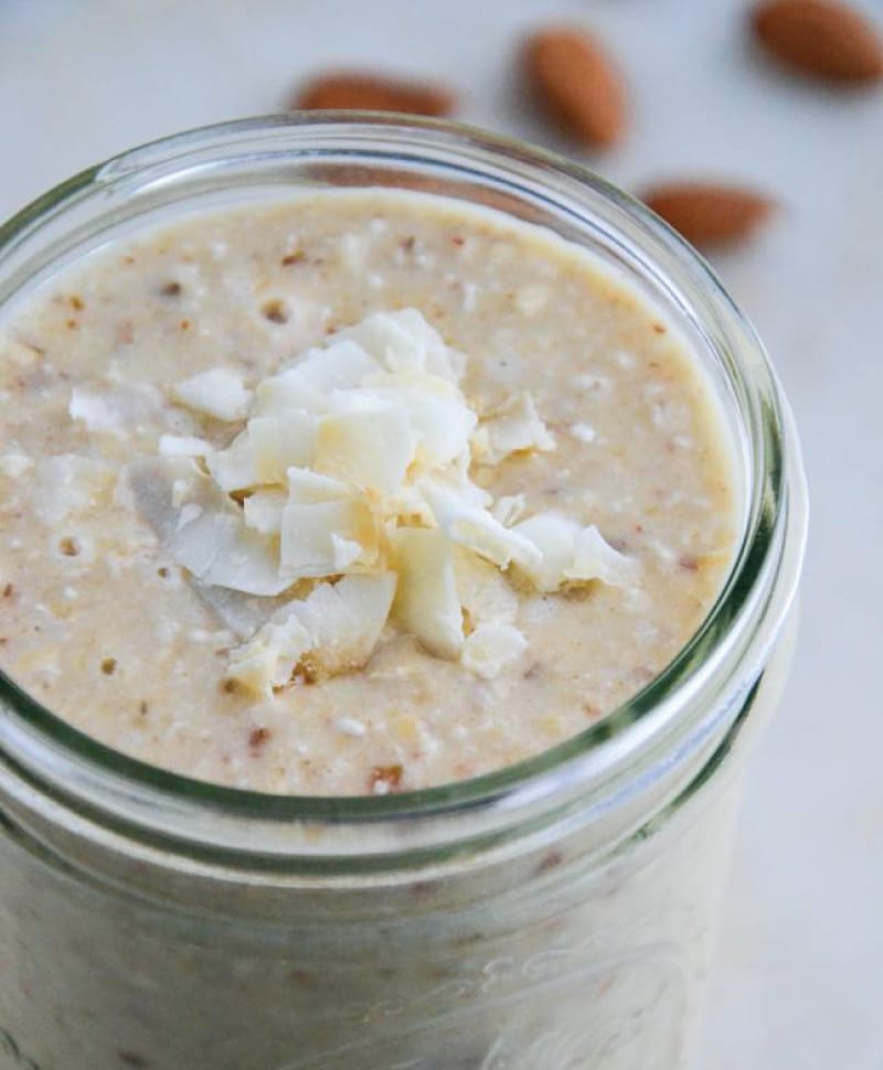 Coconut almond smoothie in a ball jar on a marble table with coconut flakes.