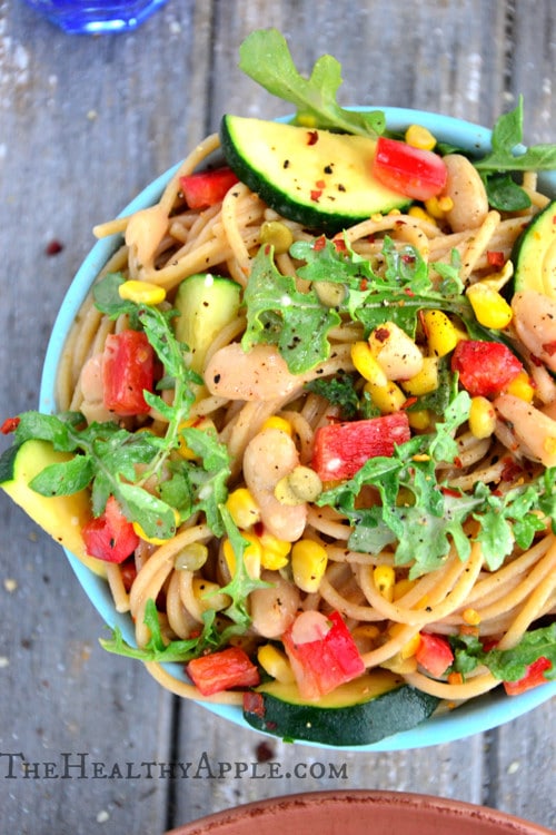Creamy-Gluten-Free-Dairy-Free-White-Bean-Pasta-Recipe11 A bowl of pasta topped with corn, white beans, zucchini, arugula, and bright pops of red pepper.