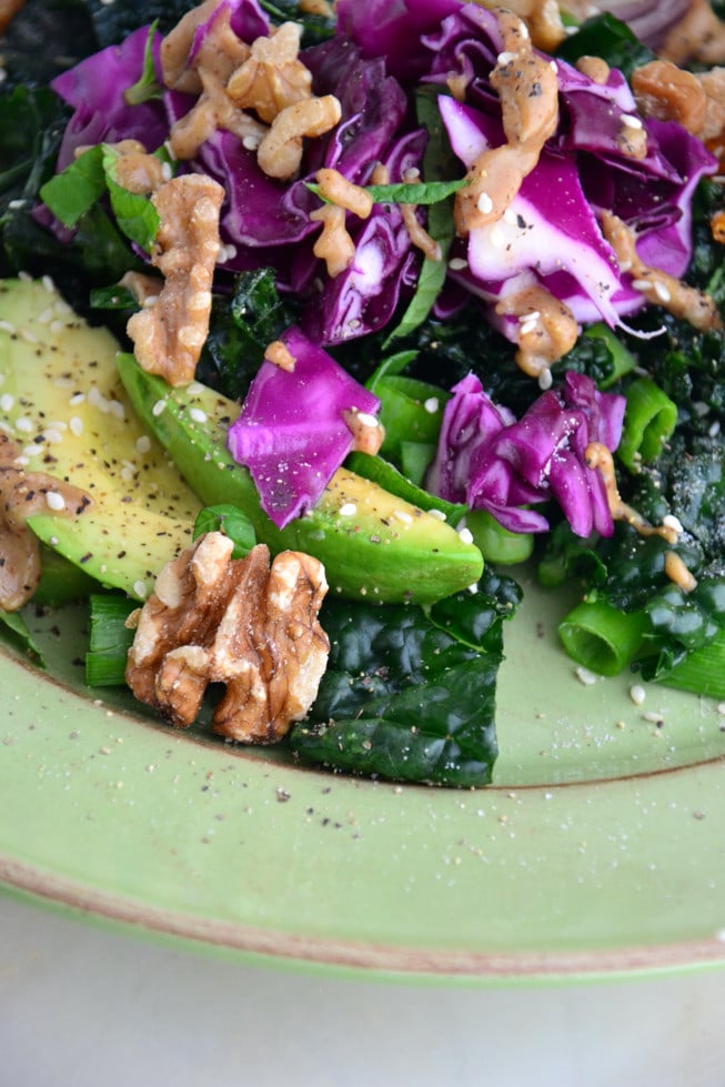 Kale avocado salad with a dairy-free creamy almond dressing on a green plate served for lunch.