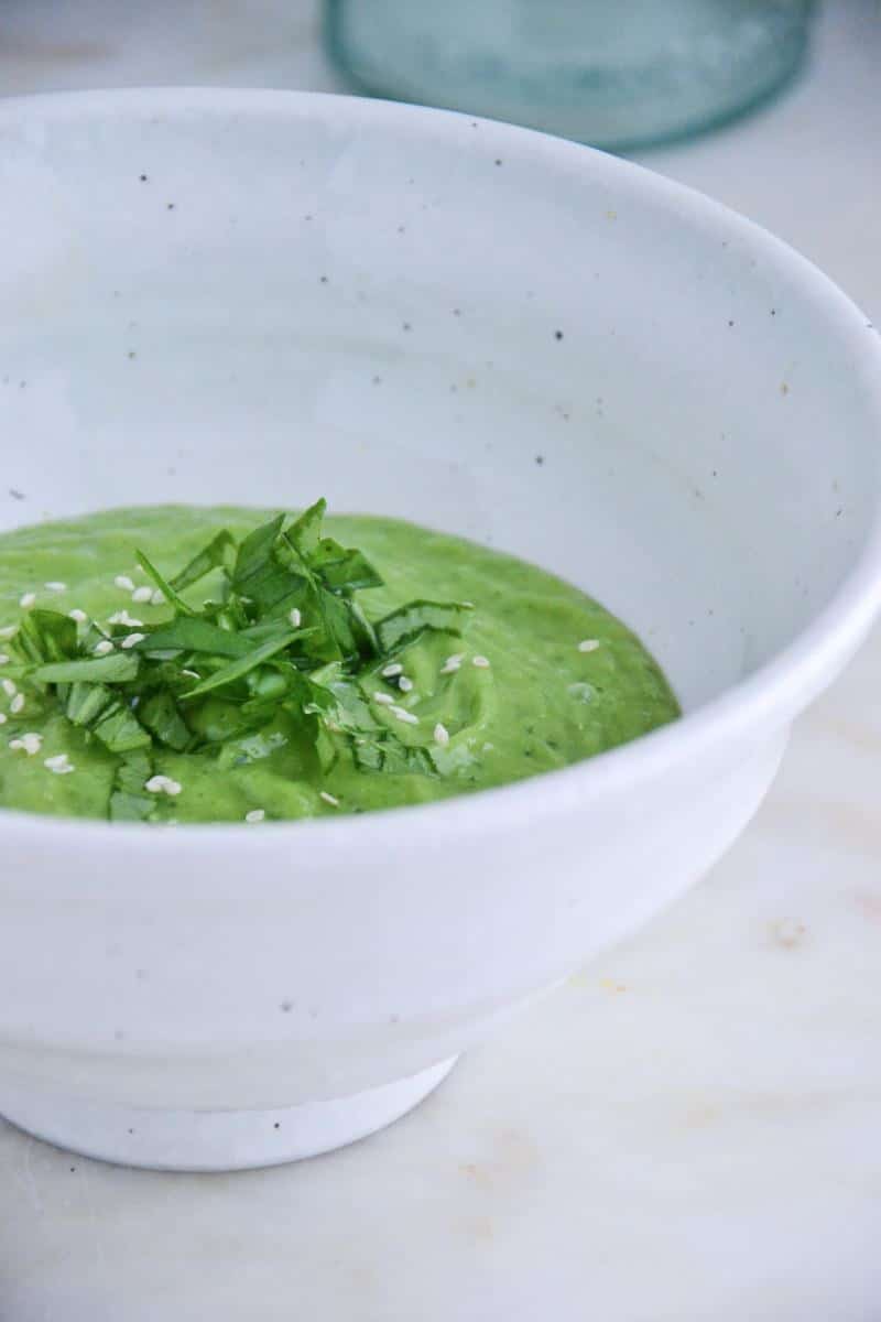 A deliciously bright green soup close up in a big white bowl.