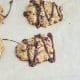 Freshly baked oatmeal cookies on parchment paper, with a drizzle of chocolate sauce on top