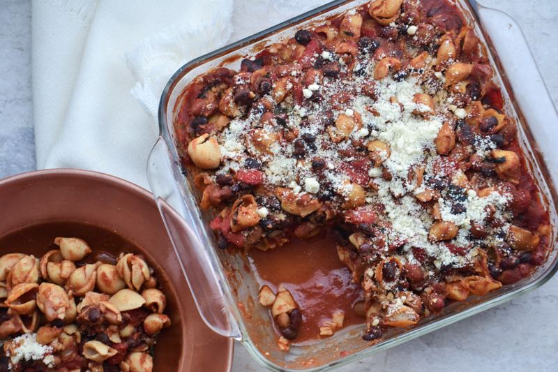 A baked casserole filled with gluten free pasta shells and a red chili.