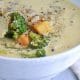 A serving of white soup with broccoli and sweet potato chunks.