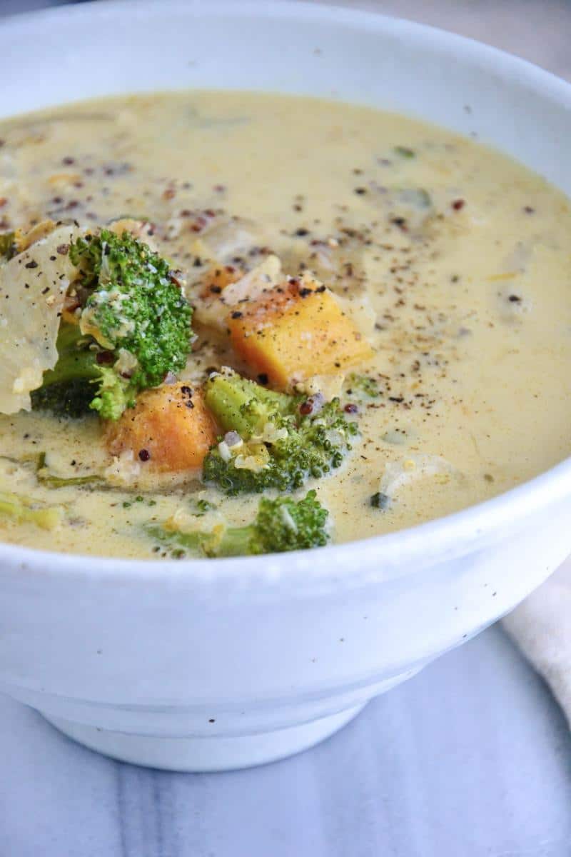 A serving of white soup with broccoli and sweet potato chunks.