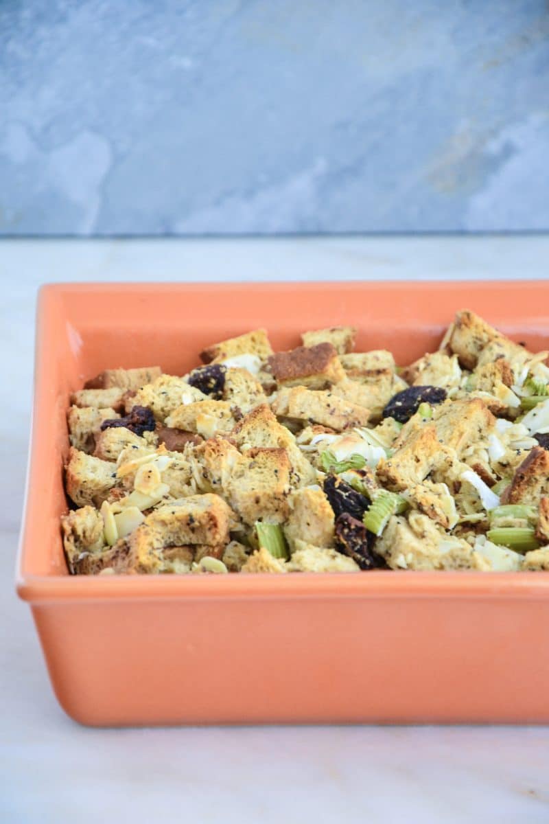 An orange baking dish of gluten-free stuffing on a white counter.