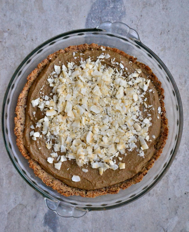 Beautiful chocolate cream pie served in a glass pie dish on a marble table.