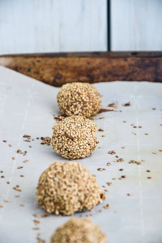 Gluten-Free Falafel hot out of the oven on a rimmed baking sheet with parchment paper and sesame seed coating.