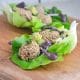 Gluten-Free Falafel in a large lettuce leaf with a cherry tahini vegan falafel dressing on a wooden serving board.