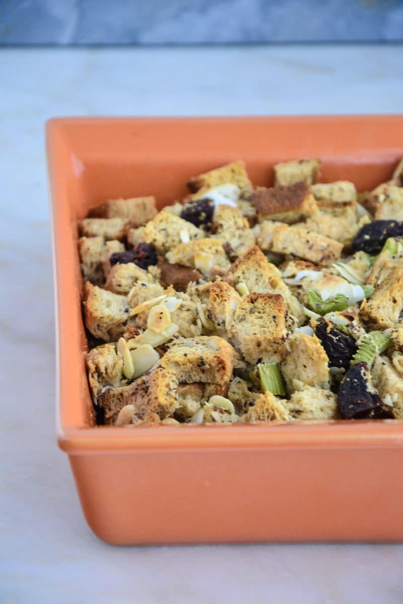 A square dish of gluten-free stuffing, including toasted bread cubes and green celery bits.