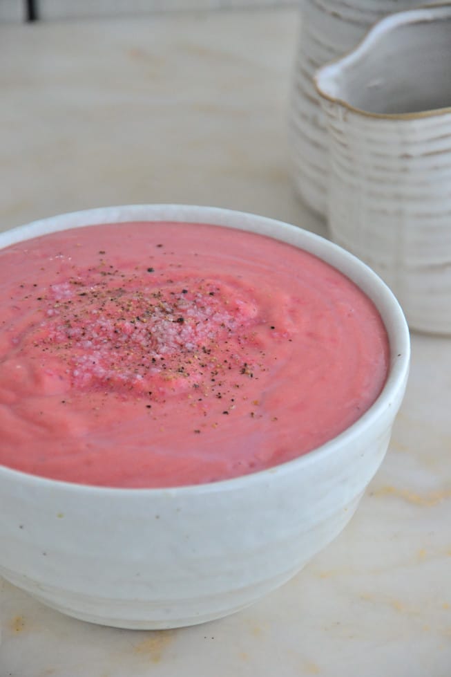 This healthy sweet potato soup is pureed to creamy perfection and served in a beautiful white bowl on a marble table.