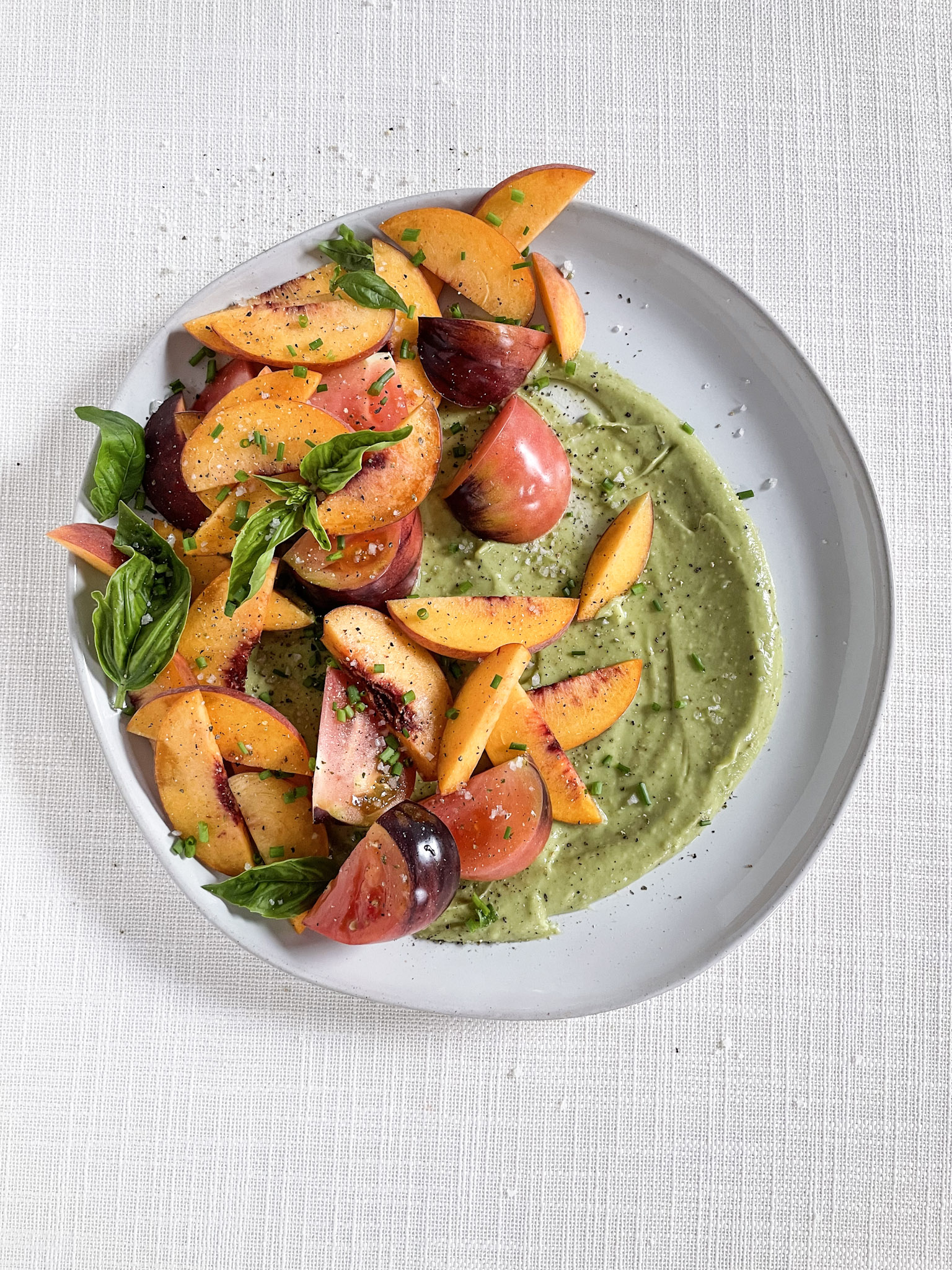 peach and heirloom tomato salad with creamy avocado dressing on a white tablecloth