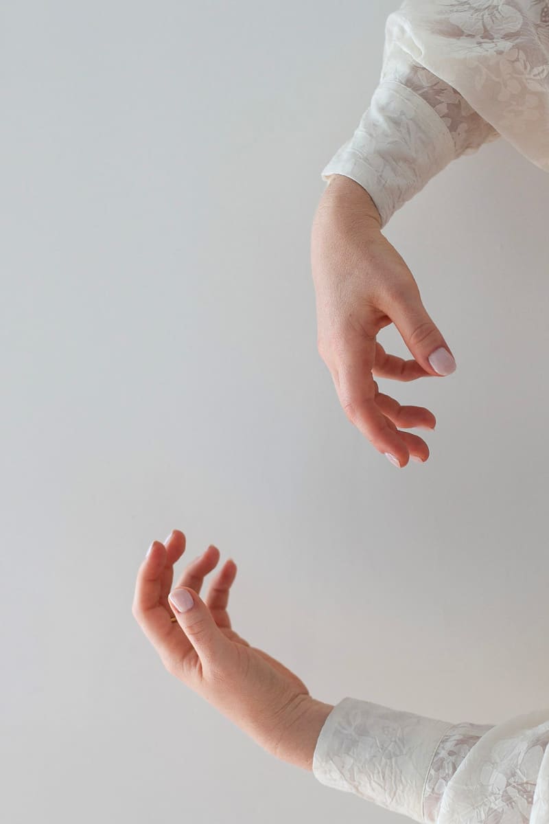 Two arms and hands, one facing up and one facing down making a circular motion with a plain background