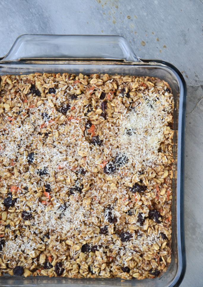 Baking dish full of baked oatmeal spotted with orange carrot and raisins.