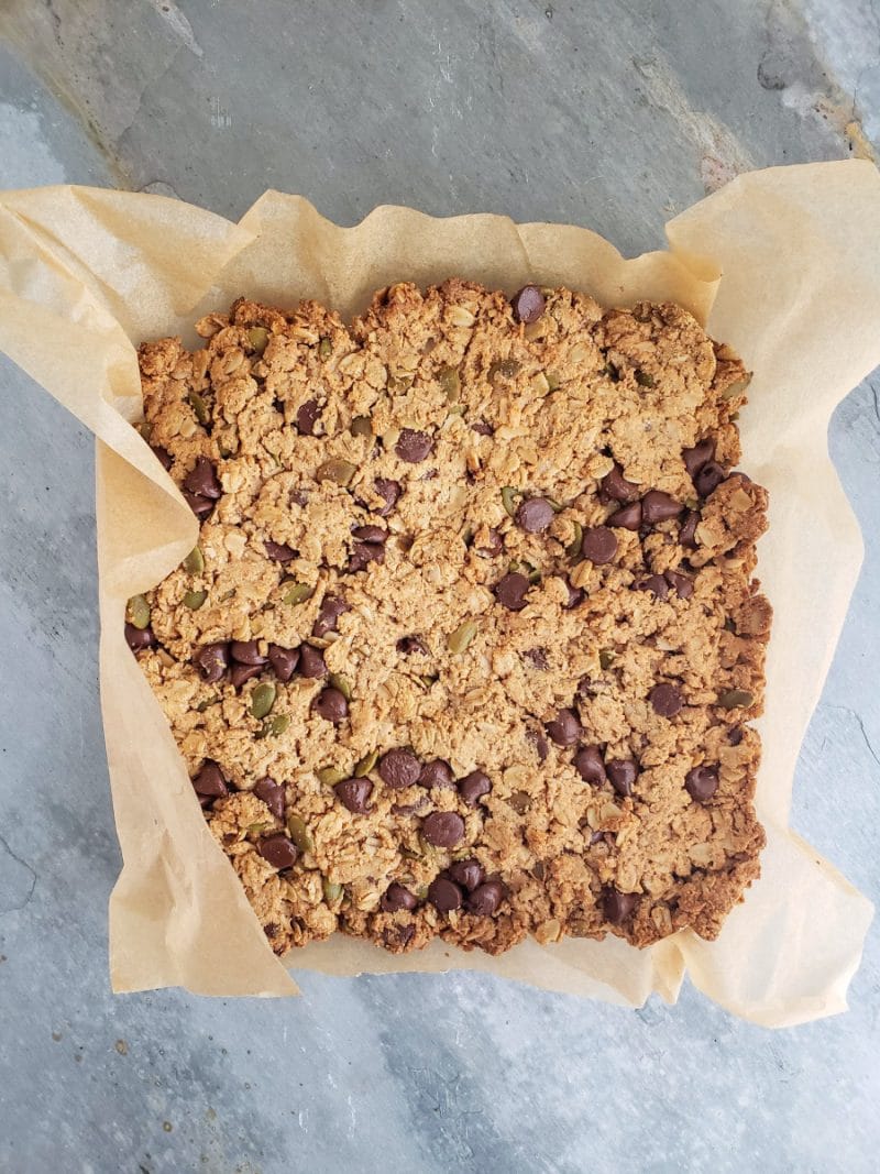 An overhead shot of freshly baked pumpkin seed chocolate chip bars in a square baking dish.