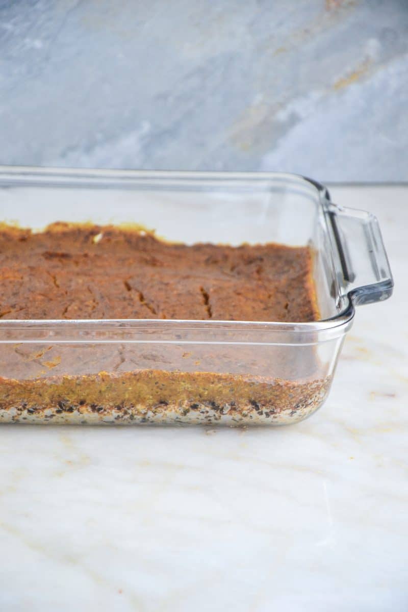A glass baking dish filled with pumpkin pie on top of a homemade oatmeal crust.