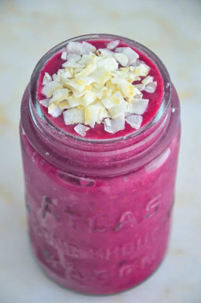 Red velvet beet smoothie in a glass jar on a marble table top.