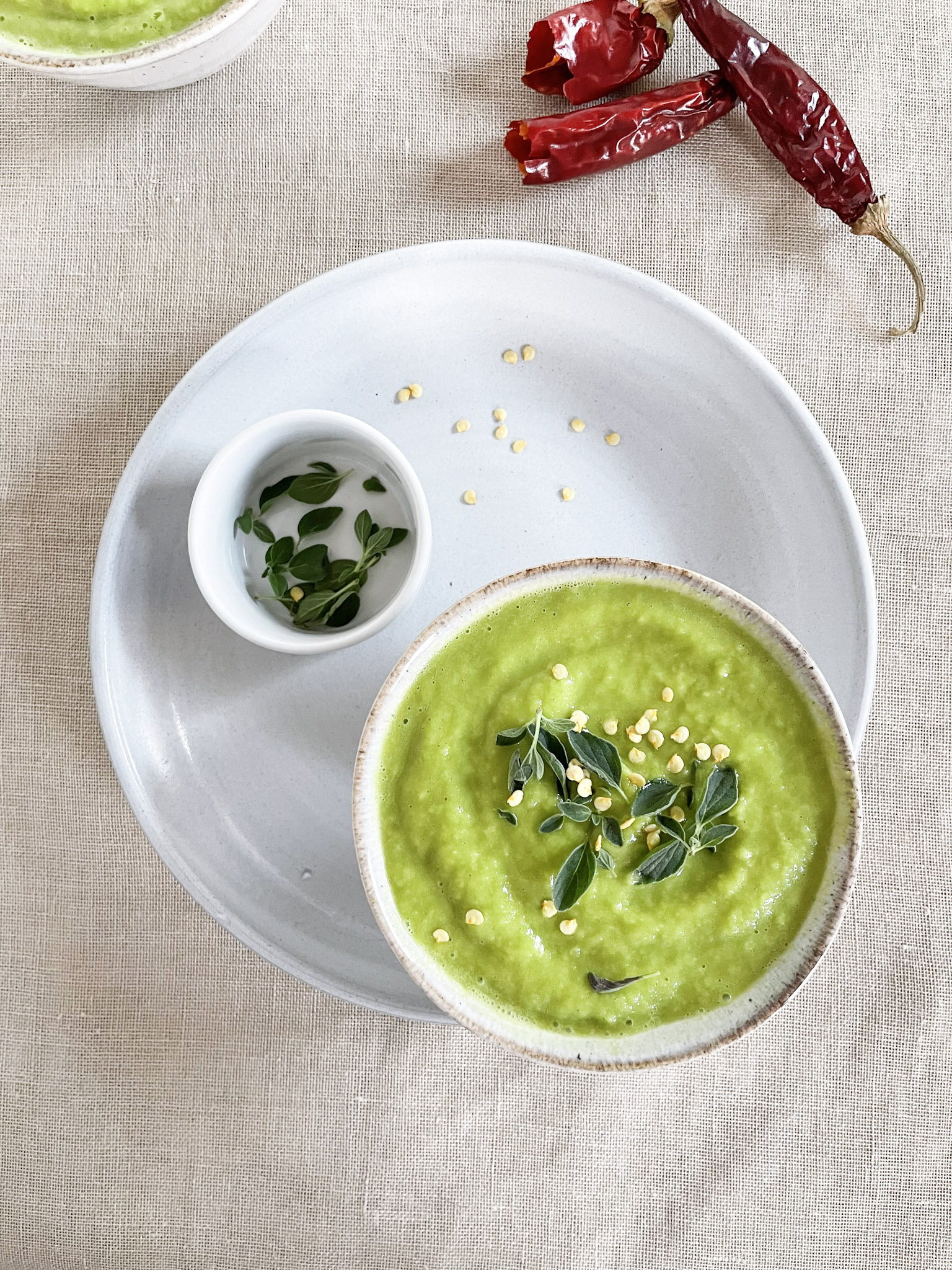 roasted zucchini soup with fresh oregano in a ceramic bowl with chili peppers