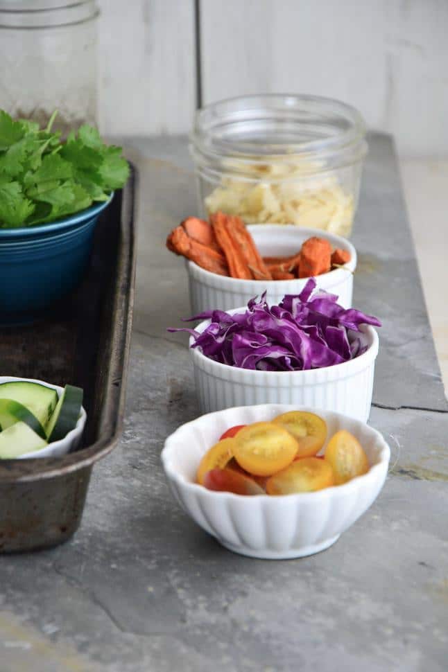 A spread of some of the cute carrot and apple salad ingredients prepped in individual bowls and ready to combine.