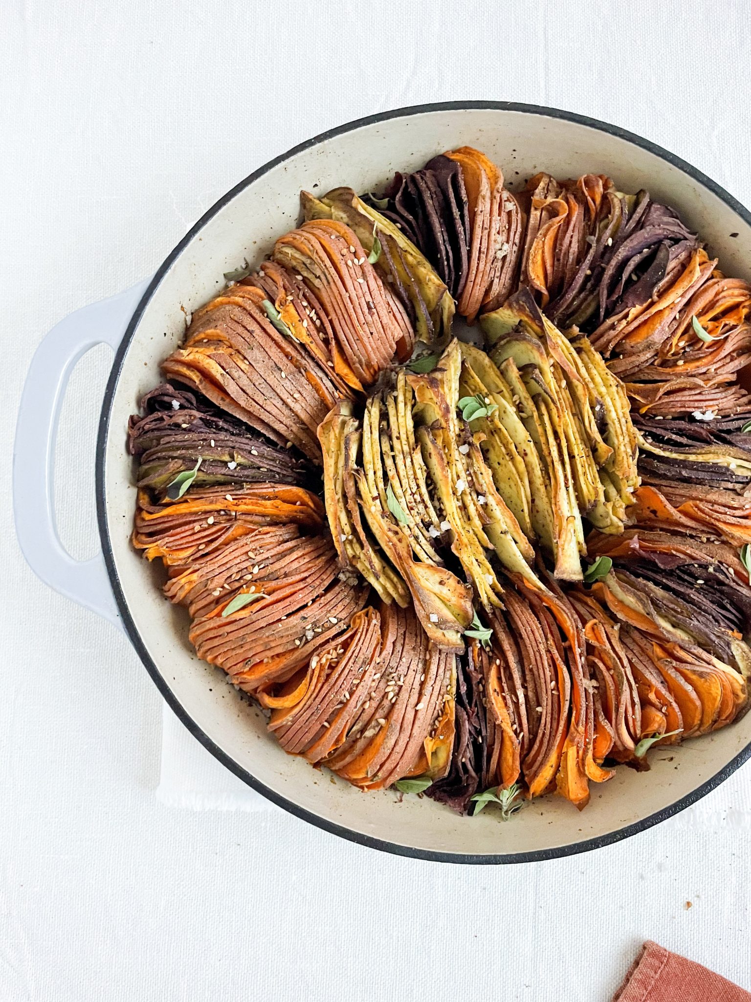 Sweet potato tian recipe on white linen with fresh oregano garnish