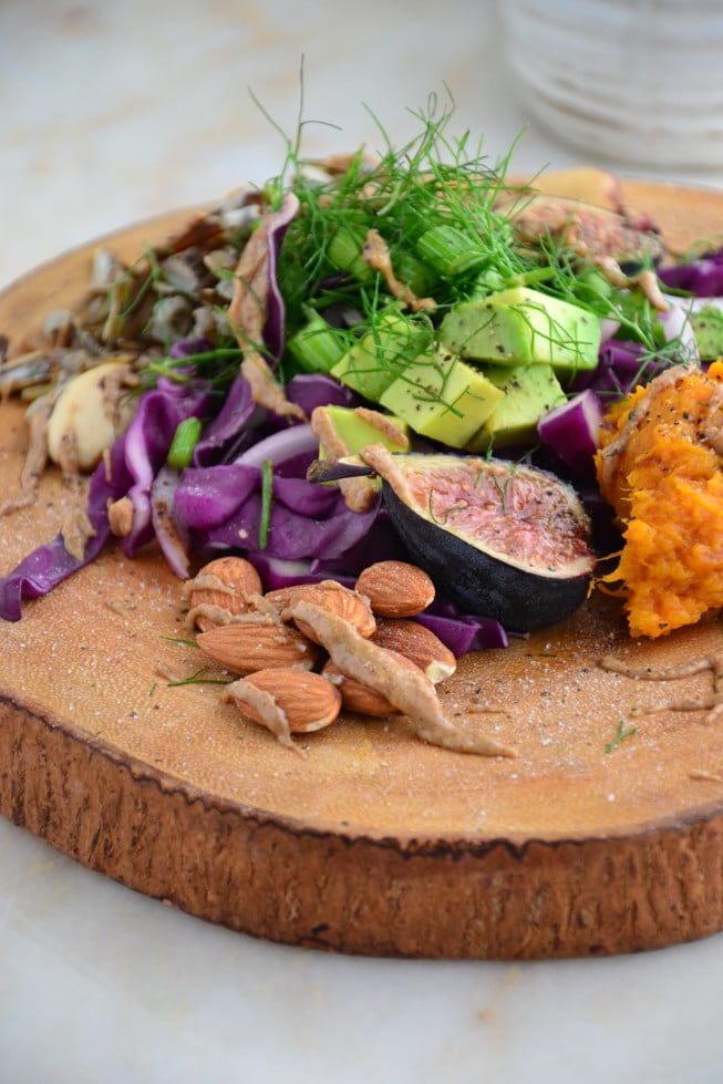 An easy tapas party platter that is filled with lots of cold fresh vegetables and wild rice on a wooden platter.