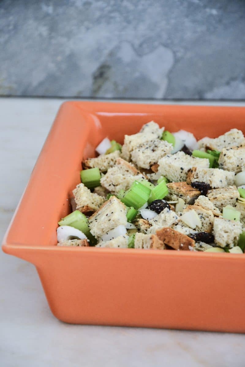 Gluten-free stuffing all mixed together in an orange square pan, ready to go in the oven.