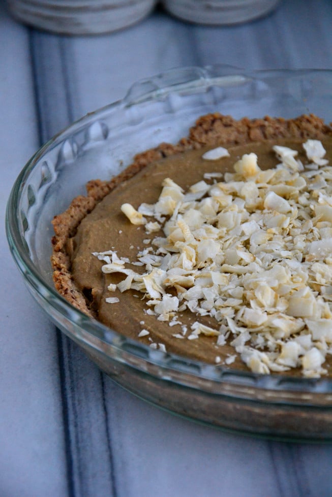 Beautiful dairy-free chocolate cream pie served in a glass pie dish on a white and gray marble table.