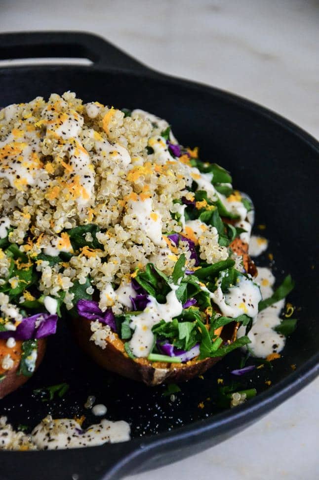 Roasted sweet potato stuffed with quinoa and greens on a skillet.