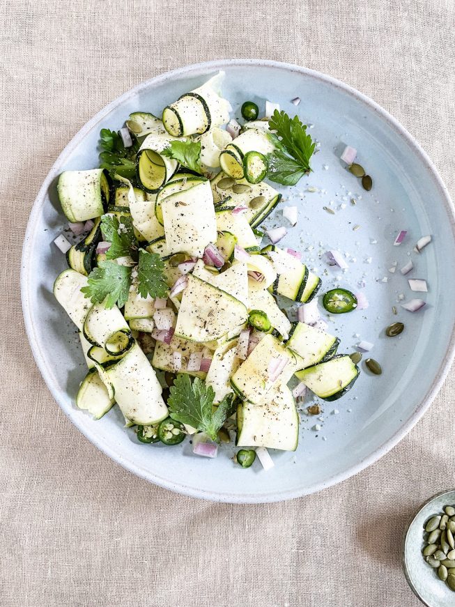 A salad plate filled with zucchini ribbons, jalapeno slices, red onion pieces, and more.